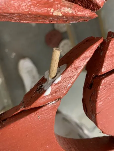 Tourillon de bois collé dans l’assemblage d’un volet rouge en réparation