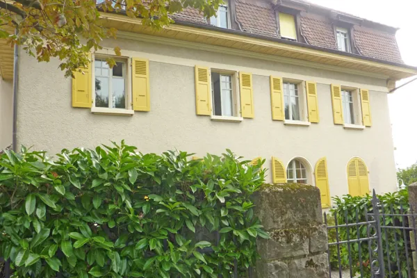 Volets jaunes sur façade claire, fenêtres à petits carreaux